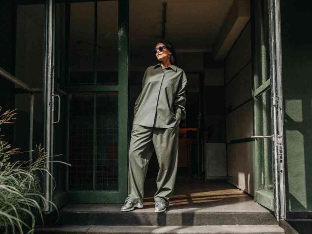 Woman in olive green outfit standing in doorway.