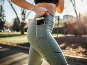 Woman running in green leggings with phone pocket