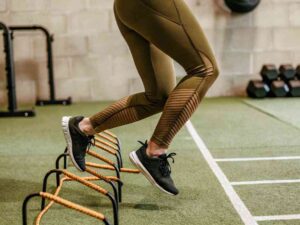 Woman jumping hurdles in olive green leggings