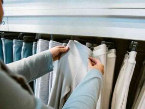 Hands inspecting light gray leggings on clothing rack