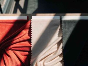 Red, cream, and green velvet swatches arranged in sunlight