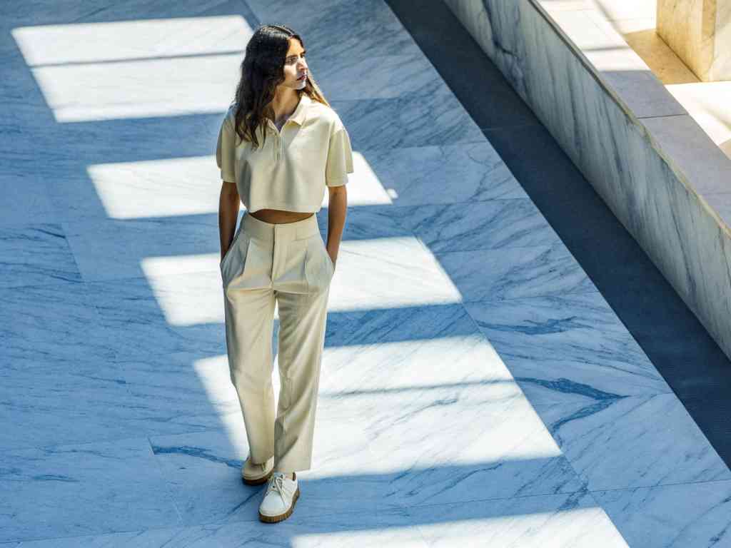 Woman in cream set walking on marble floor.