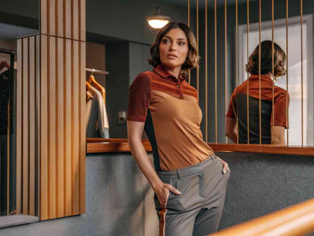 Woman in brown and orange polo indoors.