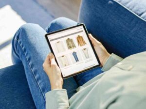 Person shopping online for clothes on tablet.