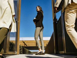 Woman in striped pants and blazer walking through outdoor gates