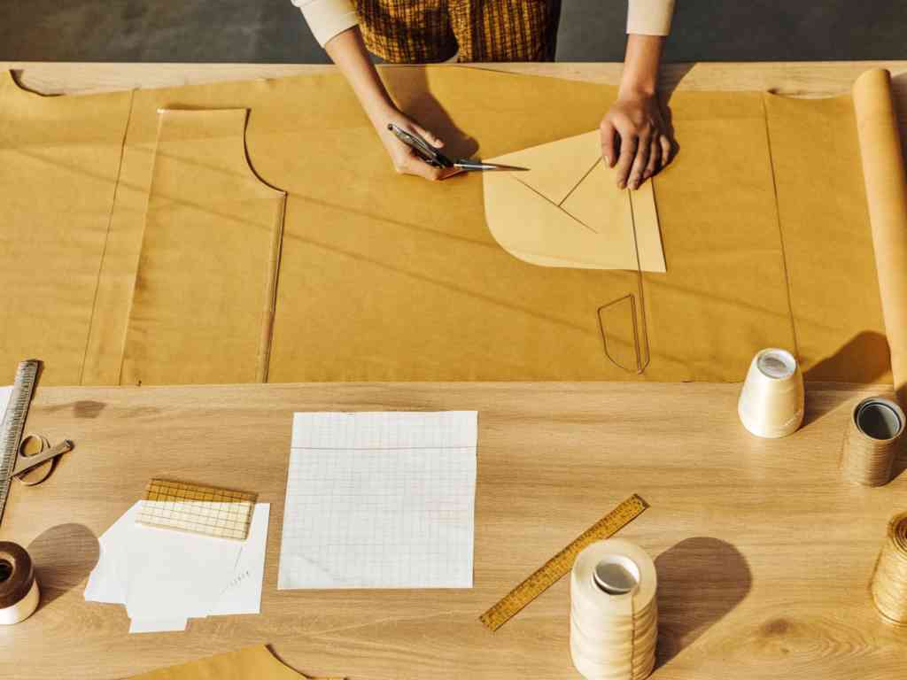 Designer cutting brown paper patterns on a wooden table