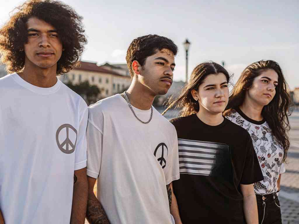 Group of young adults wearing peace symbol and abstract graphic shirts.