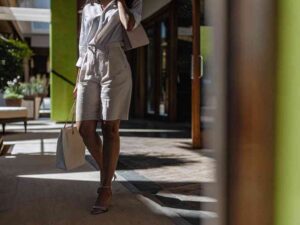 Stylish woman wearing patterned shorts and strappy heels walking through a modern shopping plaza.