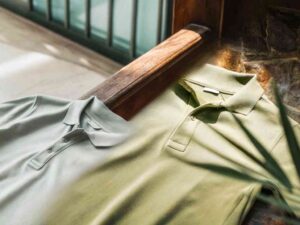 Two polo shirts in natural sunlight on wooden bench display.