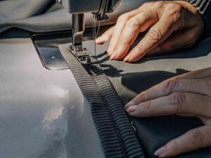 Close-up of hands sewing ribbed fabric on machine.