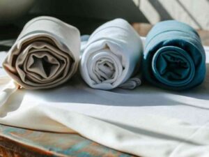 Rolled fabric in beige, white, and teal on soft surface.