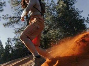Woman running down sandy hill in rust-colored cargo shorts