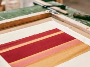 Close-up of red and mustard screen-printed graphic on fabric sheet.