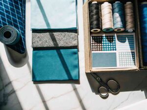 Blue-toned fabrics, threads, and swatches in a sewing kit.