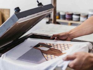 Hands lifting printed shirt from heat press