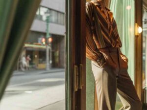 Man in striped shirt leaning by window in sunlight