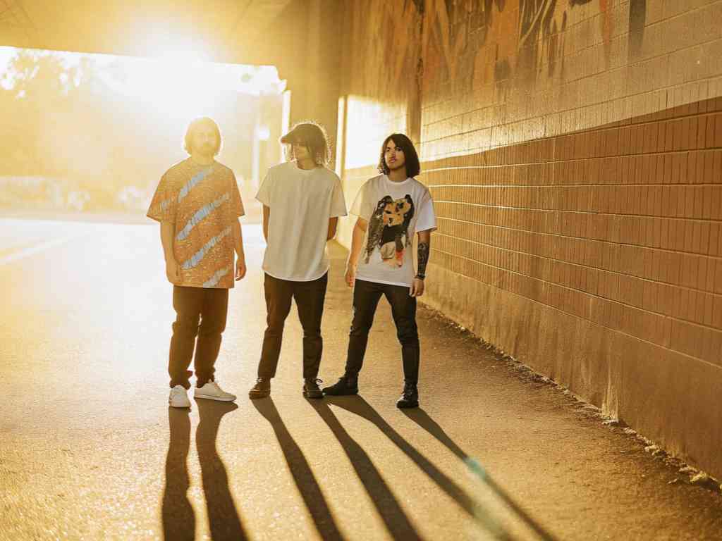 Three men in graphic and plain t-shirts in golden sunset light