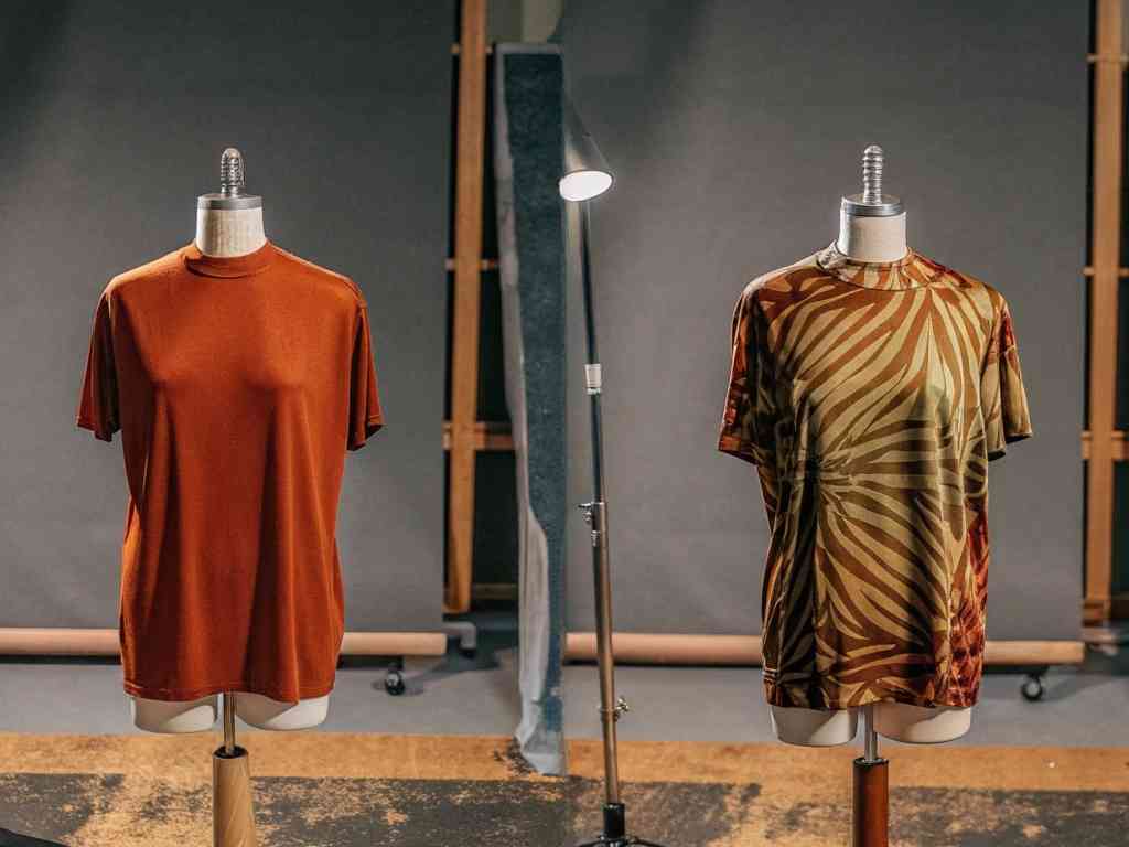 Two mannequins displaying plain and patterned brown T-shirts