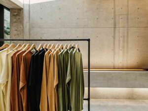 Colorful t-shirts on rack in modern minimalist showroom.