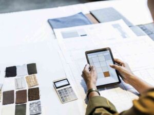 Designer reviewing textile swatches and plans using a tablet.