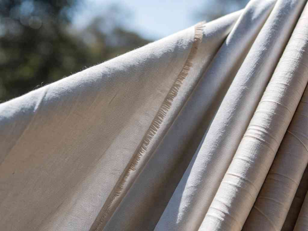 Close-up of folded cream-colored fabric in sunlight.