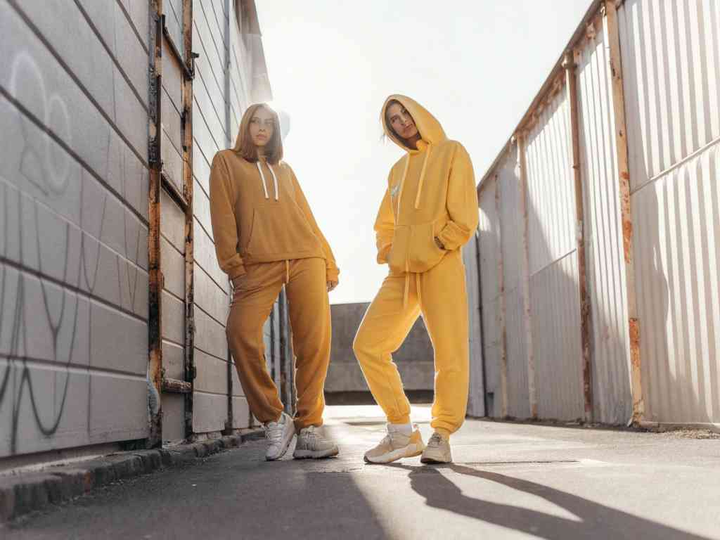 Two women in yellow hoodies and sweatpants outdoors