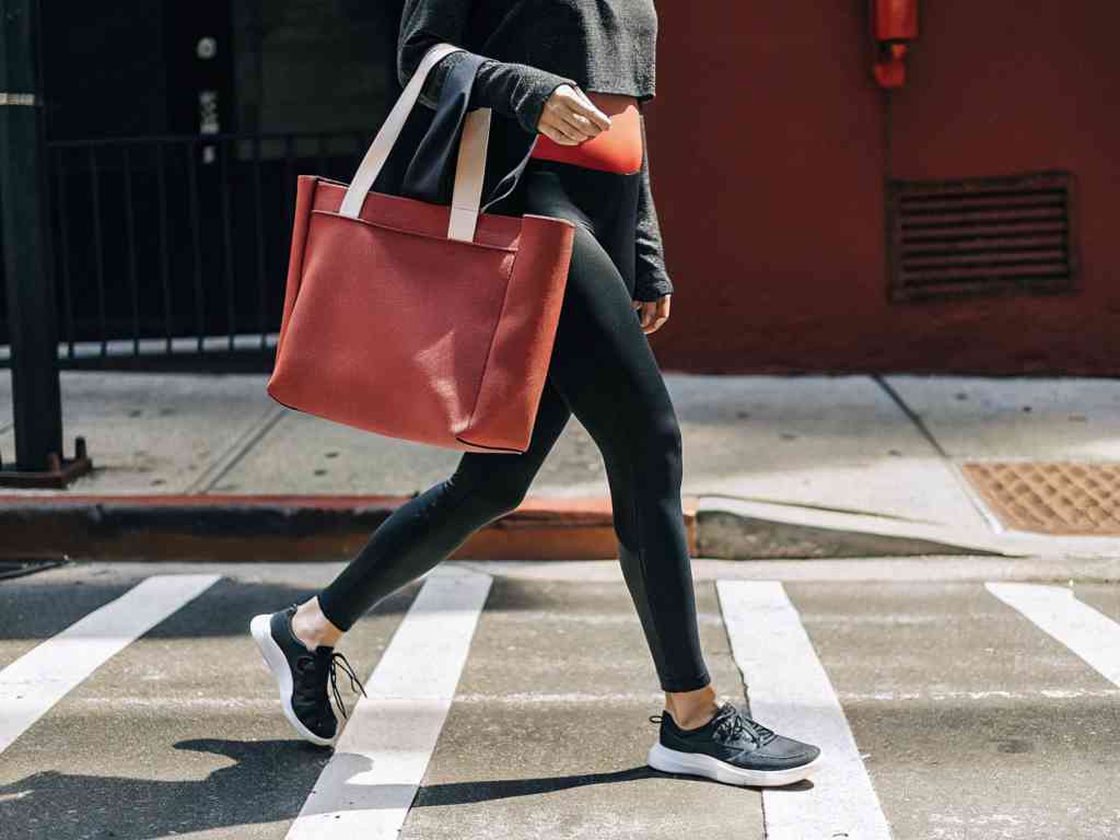 Woman in black leggings walking with red tote bag