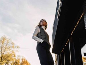 Confident woman in vest standing outside coffee shop