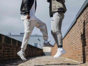 Two people jumping in jogger pants on a rooftop