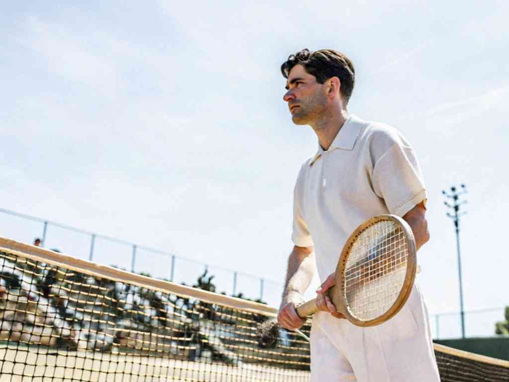 Man in vintage-style tennis outfit holding wooden racket