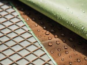 Close-up of water droplets on different textured fabrics, highlighting waterproof and breathable materials.