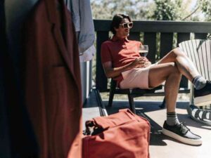 Man in red polo and pink shorts relaxing on a sunny balcony