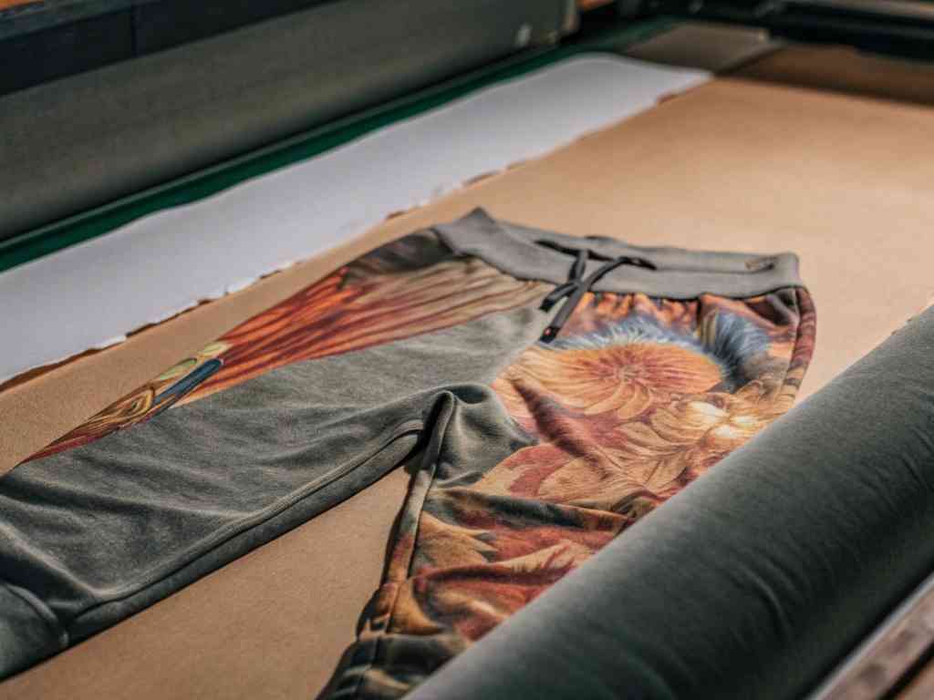Custom printed sweatpants with colorful floral artwork on fabric table