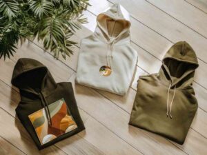 Flat lay of three folded hoodies with earthy tones and prints