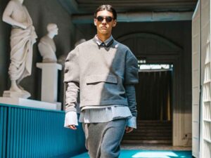 Male model in structured grey outfit walking in museum hallway