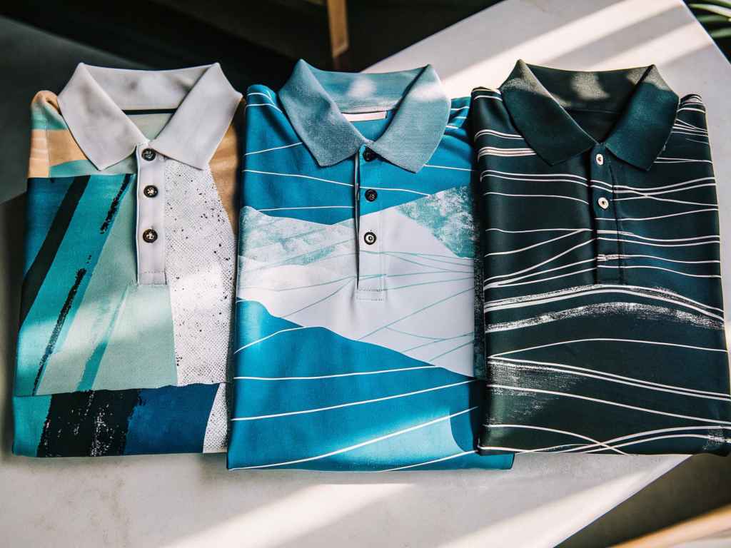 Flat lay of blue abstract polo shirts with graphic prints.