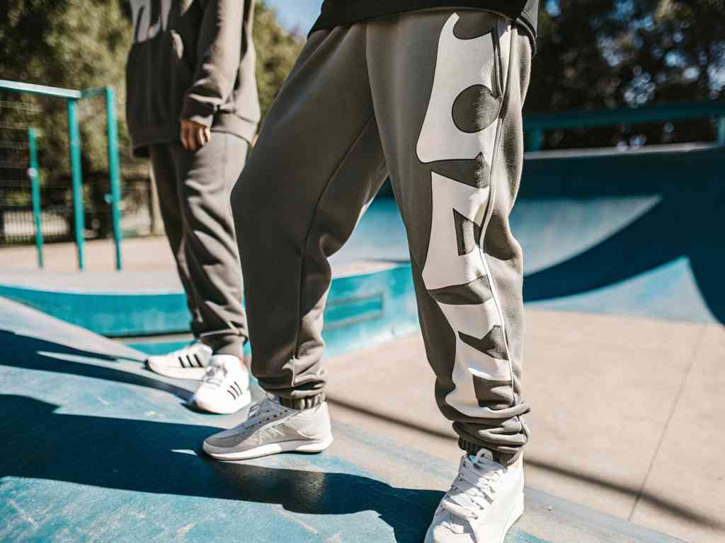 Gray fleece joggers with bold white side logo at skate park