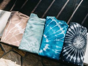 Folded tie-dye t-shirts in earthy blue and black tones.