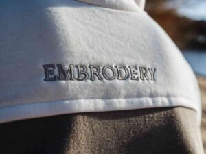 Close-up of “EMBROIDERY” stitched on a white hoodie