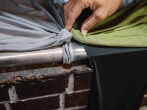 Hand comparing fabric stretch and seams of grey and green garments.