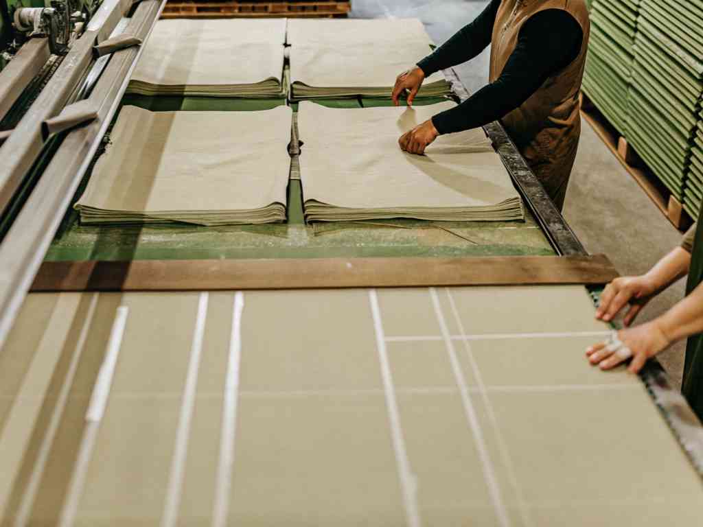 Workers folding and organizing sheets of material in a factory setting.