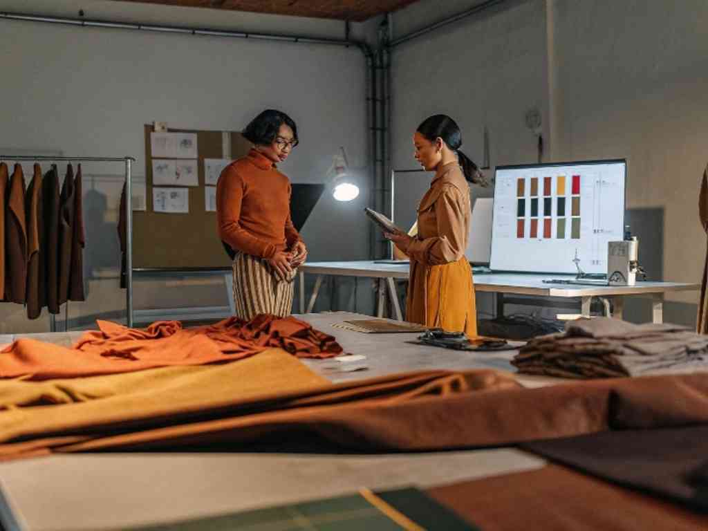 Designers discussing fabric samples and color palettes in a fashion studio.