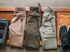 Folded jogger pants in neutral tones with accessories and shoes.