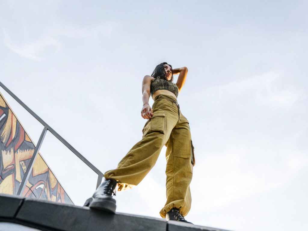 Woman in cargo pants and crop top posing on rooftop