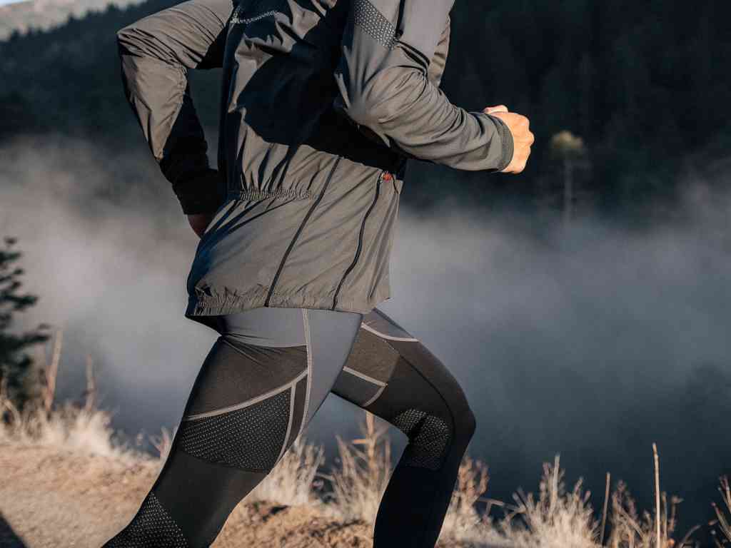 Close-up of runner in black technical sportswear sprinting on mountain trail