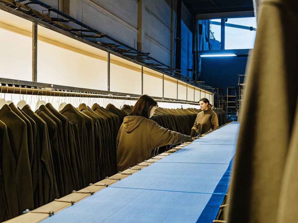Workers inspecting hoodies on production line in industrial garment facility