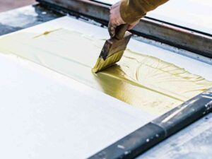 Close-up of yellow ink being spread across screen with squeegee