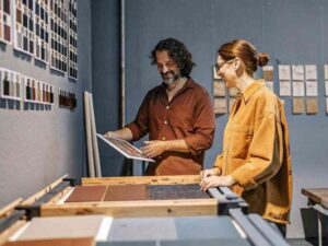 Two professionals discussing fabric samples in a design studio with swatch walls.