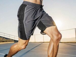 Male athlete wearing gray running shorts with mesh panels on court