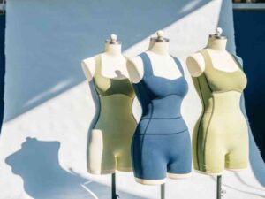 Three mannequins wearing green and blue fitted athletic unitards in studio.